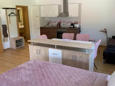 a kitchen with a counter and pink chairs in a room at Apartmaji Prʼ nas in Laško