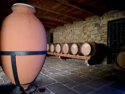 a large vase sitting next to a row of wine barrels at MEGA in Prvačina