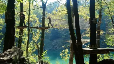 two people on a suspension bridge over a lake at MEGA in Prvačina