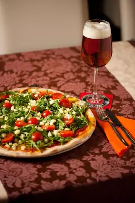 a pizza sitting on a table next to a glass of beer at Gold Club Hotel & Casino in Ajdovščina