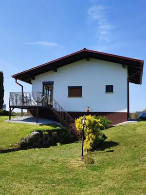 a white house with a balcony on a grass field at APARTMA KAPELSKI FANT in Sveti Jurij ob Ščavnici