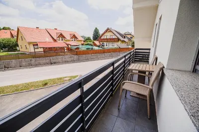 a balcony with two chairs and a view of a house at Mojčin Pisker Apartment House in Kranj