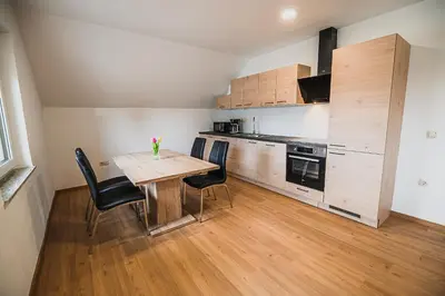 a small kitchen with a wooden table and chairs at Mojčin Pisker Apartment House in Kranj