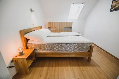 a large bed in a room with a wooden floor at Mojčin Pisker Apartment House in Kranj