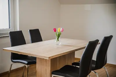 a wooden table with a vase of flowers on it at Mojčin Pisker Apartment House in Kranj