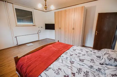 a bedroom with a bed with a red blanket on it at Mojčin Pisker Apartment House in Kranj
