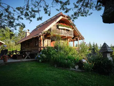 a log cabin with a balcony with flowers on it at Chalets Toplak in Sveti Duh na Ostrem Vrhu
