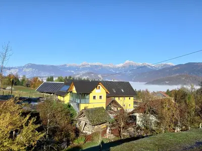 a yellow house with solar panels on top of it at B&B family room Tubej in Bohinj