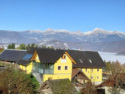 a yellow house with solar panels on top of it at B&B family room Tubej in Bohinj