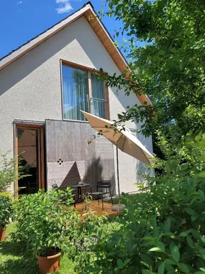 a patio with a table and an umbrella in front of a house at Apartma Hiša 6 in Bohinj