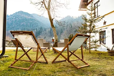 two chairs sitting on the grass in front of a house at Apartmaji pri Dravi in Podvelka