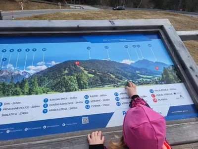 a child is looking at a screen with mountains on it at APARTMA 27 in Kranjska Gora