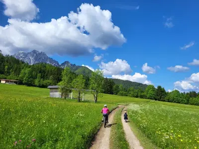 a woman and a child riding a bike on a dirt road at APARTMA 27 in Kranjska Gora