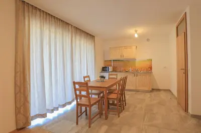 a dining room with a table and chairs and a kitchen at Apartments Mulej in Bled