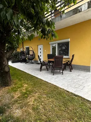 a patio with chairs and a table next to a yellow wall at RIAD Apartments Premium in Zgornje Škofije