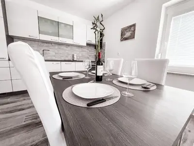 a dining room table with white chairs and a bottle of wine at RIAD Apartments Premium in Zgornje Škofije