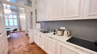 a kitchen with white cabinets and a sink and a table at AB Ljubljana - Breg Apartments in Ljubljana