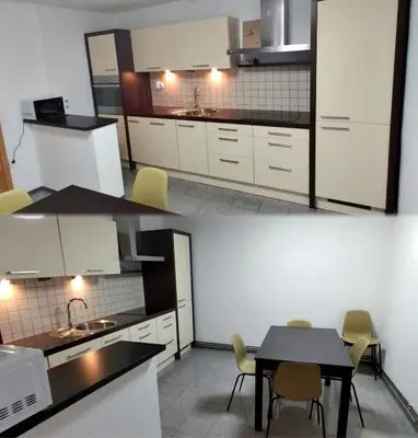 a kitchen with white cabinets and a table and chairs at Apartma VAL - Maribor in Maribor