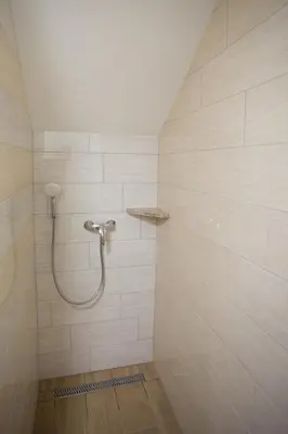 a shower with a hose in a white tiled bathroom at APARTMAJI HUBI in Bled