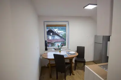 a kitchen with a table and chairs and a window at APARTMAJI HUBI in Bled