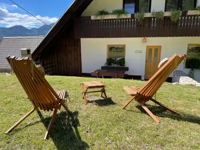 two chairs sitting in the grass in front of a house at Apartma Korošec in Srednja Vas v Bohinju