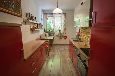 a kitchen with red cabinets and a large window at Apartma Pic Ros in Kojsko