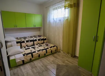 a room with three beds and green cabinets at Apartma Pic Ros in Kojsko