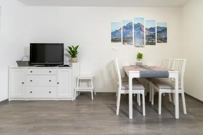 a dining room with a white table and a tv at Apartma pri lipi in Bohinj