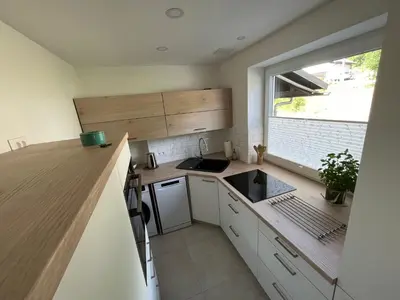 a small kitchen with white cabinets and a window at Pod Galetovcem in Bohinjska Bela