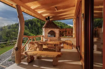 a wooden patio with a table and a fireplace at Lake Cottage - Koča ob jezeru in Nazarje