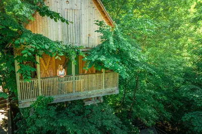 a woman standing on a deck in a tree house at Garden Village Bled in Bled