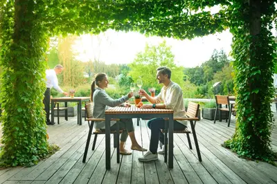 two people sitting at a table with glasses of wine at Garden Village Bled in Bled
