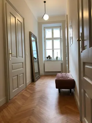 a hallway with a mirror and a ottoman in front of a door at Riverside apartment in Ljubljana