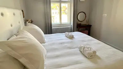 a white bed with two slippers on top of it at Riverside apartment in Ljubljana