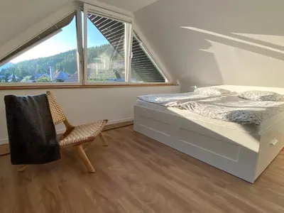 a bedroom with a bed and a chair and a window at Apartment Židana marela - Attic with a View in Kranjska Gora