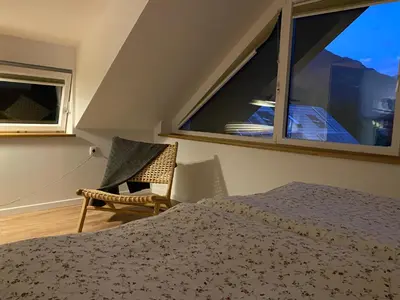 a bedroom with a bed and a chair and a window at Apartment Židana marela - Attic with a View in Kranjska Gora
