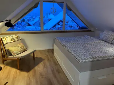 a bedroom with a bed and a large window at Apartment Židana marela - Attic with a View in Kranjska Gora