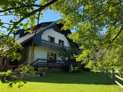 a large white house with a porch and trees at Apartment Židana marela - Attic with a View in Kranjska Gora