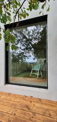 a window of a house with a chair on a patio at HOUSE G in Dekani
