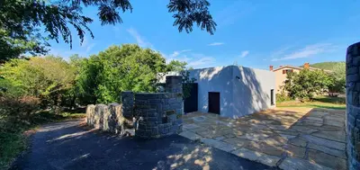 a house with a stone retaining wall in a yard at HOUSE G in Dekani