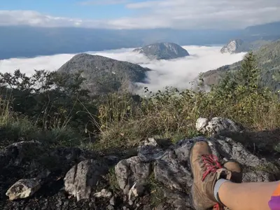 a person sitting on a rock looking at the clouds at Chalet Hike&Bike above Bohinj valley in Bohinj