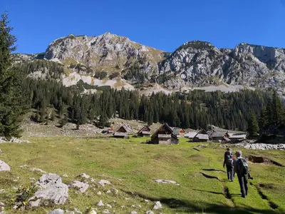a group of people walking on a grassy hill with mountains at Chalet Hike&Bike above Bohinj valley in Bohinj