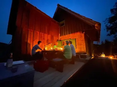a group of people sitting at a table outside of a barn at Chalet Hike&Bike above Bohinj valley in Bohinj