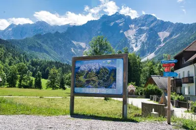 a sign in a field with mountains in the background at Apartma Vila Kočna in Zgornje Jezersko