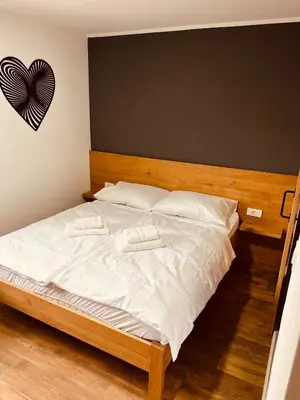 a bed with two white pillows and a heart on the wall at PJagodic Hotel Cerklje - 5min to Airport - Free Parking in Cerklje na Gorenjskem
