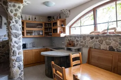 a kitchen with a table and a stone wall at Zerko Holiday Home - Vineyard Chalet With Sauna and Jacuzzi FREE in Mirna