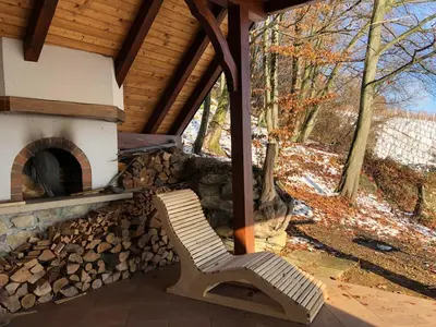 a wooden bench sitting in front of a fireplace at Vineyard cottage Skriti raj in Leskovec pri Krškem