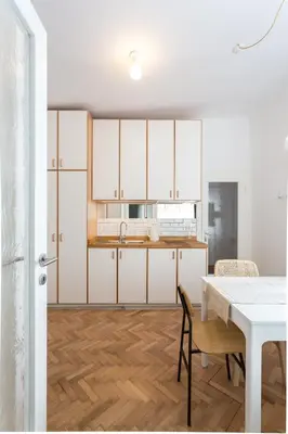 a kitchen with white cabinets and a table and chairs at KariNatura in Ljubljana