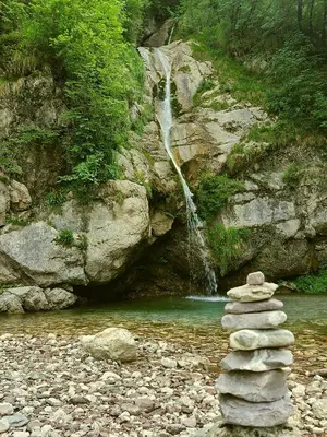 a stack of rocks in front of a waterfall at Krampez in Kobarid