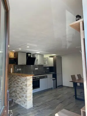a large kitchen with white cabinets and a brick wall at Apartma Ročica Dejan Uršič sobodajalec in Kobarid